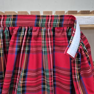 May include: Red and green plaid fabric with a white hook and loop fastener along the edge.