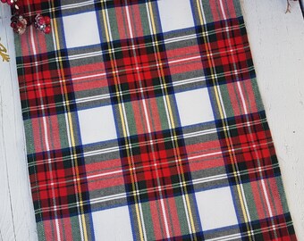 May include: Red, white, green, and blue plaid table runner. The runner has a white background with red, green, and blue plaid stripes.