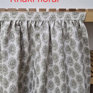 May include: Khaki floral fabric with a repeating pattern of stylized leaves. The fabric is draped over a wooden structure. The text "Khaki floral" is displayed in red at the top of the image.