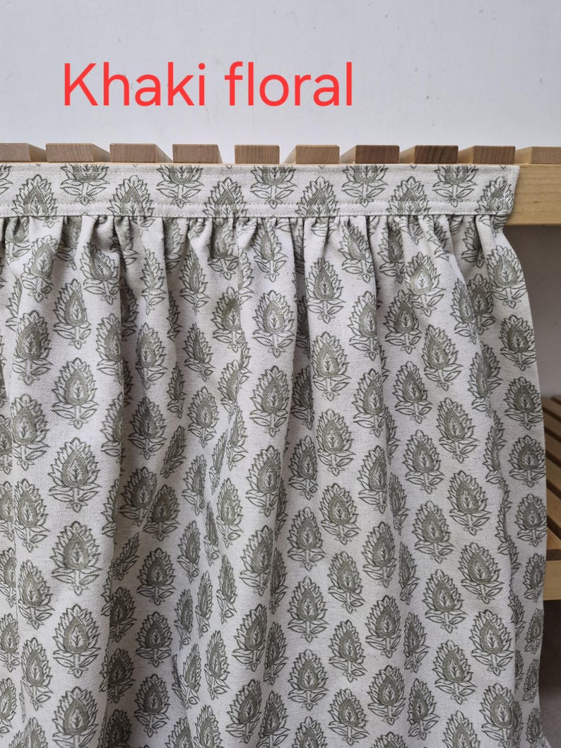 May include: Khaki floral fabric with a repeating pattern of stylized leaves. The fabric is draped over a wooden structure. The text "Khaki floral" is displayed in red at the top of the image.