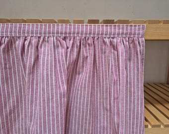 May include: A pink and white striped fabric curtain with a gathered ruffle at the top.