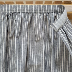 May include: A grey and white striped fabric curtain with a white velcro strap.
