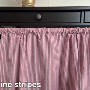 Könnte beinhalten: Ein rosa-weiß gestreiftes Stoffvorhang mit dem Text "Vine stripes" am unteren Rand.