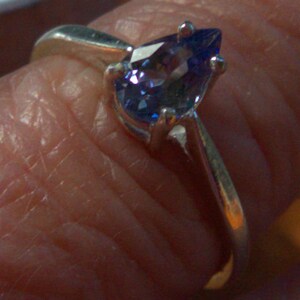 May include: A silver ring with a teardrop-shaped blue gemstone.