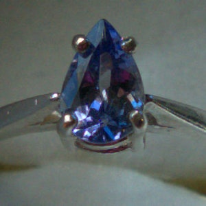 May include: A silver ring with a pear-shaped blue gemstone.