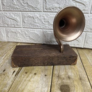 May include: A decorative, vintage-style tissue box featuring a copper-colored horn and a dark brown wooden base. The base has a rectangular shape with a slot for tissue dispensing and brass corner accents. The horn is angled upwards.