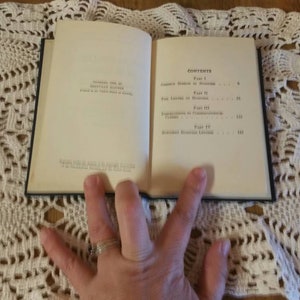 May include: An open book with a white cover and black text. The book's contents include "The Tactics of Peace" and "Negotiated Economic Recovery".