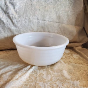 May include: A white ceramic mixing bowl with a smooth, rounded surface. The bowl is empty and appears to be in good condition.