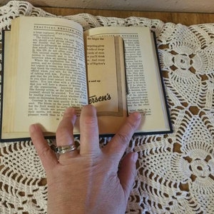 May include: An open book with a black cover and white pages. The book is titled "Practical English for Business". The pages are open to a section on "The Importance of Truthfulness". A hand is holding the book open.