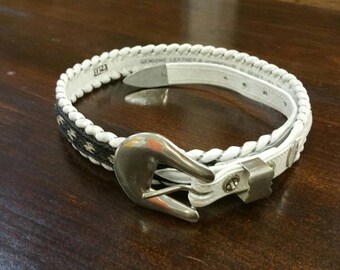 May include: White leather belt with a braided design and a silver buckle. The belt has the text "GENUINE LEATHER & HANDCRAFTED" on it.