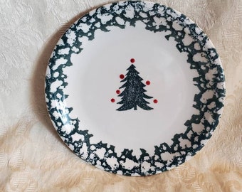 May include: White ceramic plate with a dark green speckled border. The plate features a dark green Christmas tree design in the center, with three red dots. A festive and decorative piece for holiday dining.