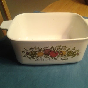 Puede incluir: Plato para hornear rectangular blanco con un diseño floral que presenta hojas verdes, tomates rojos, limones amarillos y el texto "Le Persil La Sauge".