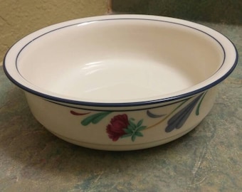 May include: A white ceramic bowl with a blue rim and floral design. The bowl features a blue, green, and red floral pattern.