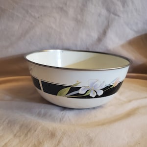 May include: White enamel bowl with a black and white floral design. The bowl has a silver rim.