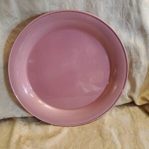 Op de afbeelding: Een grote, roze serveerschaal met een geribbeld ontwerp rond de rand.