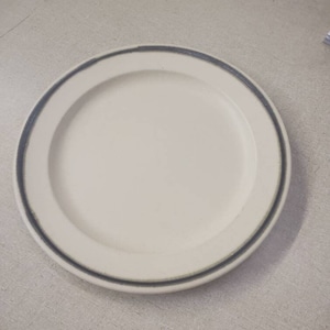 Può includere: Un piatto in ceramica bianca con un bordo sottile blu e verde.