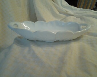 May include: White milk glass serving dish with scalloped edges and two handles. The dish is oval shaped and has a smooth, glossy finish.
