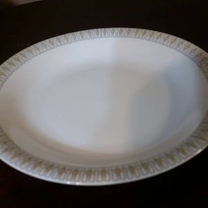 May include: A white oval serving bowl with a gold and green patterned rim.