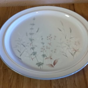 May include: A white oval platter with a floral design featuring delicate grey and brown flowers and leaves. The platter has a raised rim and a subtle blue border.