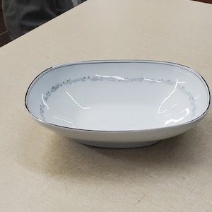 Może przedstawiać: Biała owalna miska do serwowania z srebrną krawędzią i delikatnym niebieskim wzorem kwiatowym.