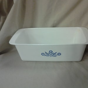 Puede incluir: Molde para pan de cerámica blanca con un diseño floral azul.