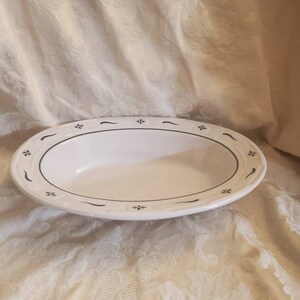 Pode incluir: Tigela oval branca com um design floral verde e preto em torno da borda.