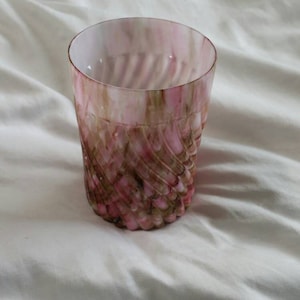 May include: A pink and brown glass tumbler with a swirl pattern. The glass is clear and has a textured surface.