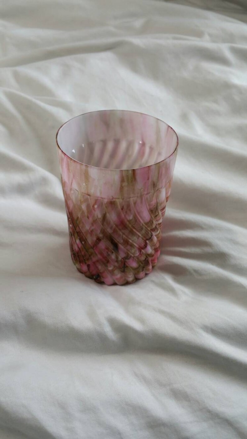 May include: A pink and brown glass tumbler with a swirl pattern. The glass is clear and has a textured surface.