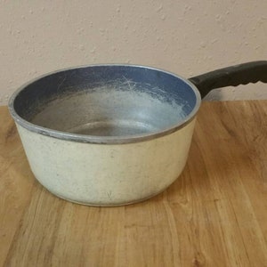 Peut inclure: Une casserole en aluminium blanche et bleue avec une poignée noire. La casserole a une finition mouchetée.