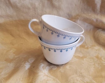 May include: Two white ceramic soup bowls with a blue snowflake pattern. The bowls are stacked on top of each other.