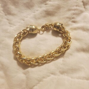 May include: A gold chain bracelet with a braided design and two round clasps.