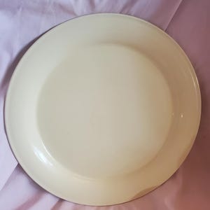 Op de afbeelding: Een grote, ronde, crèmekleurige emaille serveerschaal. De schaal heeft een licht verhoogde rand.