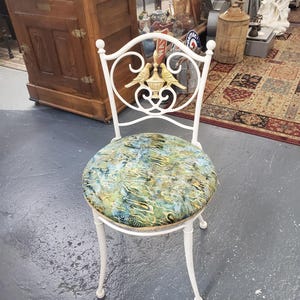 May include: White metal chair with a round, green and gold patterned seat. The chair back features a decorative design with two gold birds and a vase.