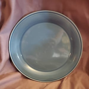 Op de afbeelding: Een lichtblauwe keramische bakvorm met een licht gegolfde rand.