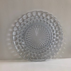 May include: A clear glass plate with a raised, bubbled rim and a starburst pattern in the centre.