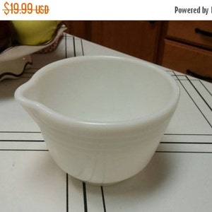 May include: White ceramic mixing bowl with a pouring spout. The bowl is on a white and black checkered surface.