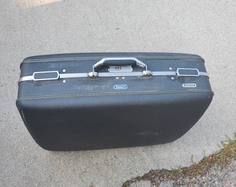 May include: A black vintage suitcase with silver accents and a blue label that says "Samsonite".