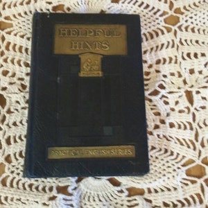 May include: A black book with gold lettering on the cover. The title is "Helpful Hints" and the subtitle is "Practical English Series".