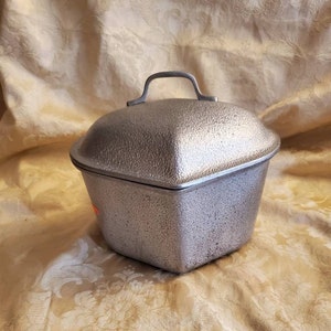 Peut inclure: Un plat à gratin en aluminium moulé, octogonal, argenté, avec une surface texturée et une poignée sur le couvercle.