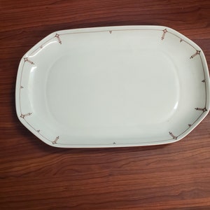 May include: A white oval serving platter with a brown decorative border. The platter has a slightly raised edge.