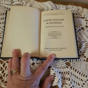 May include: A closed book titled "Good English in Business" compiled by Grenville Kleiser. The book is published by Funk & Wagnalls Company in New York and London.