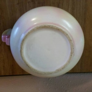 May include: A white ceramic bowl with a pink rim and a pink floral design. The bowl is glazed and has a smooth finish.