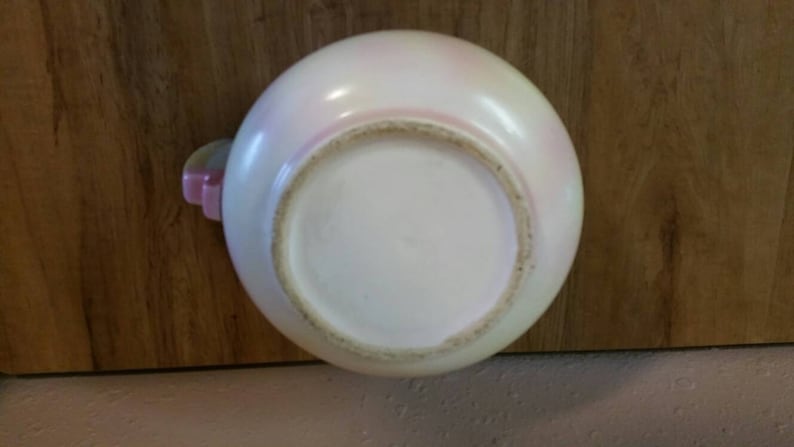 May include: A white ceramic bowl with a pink rim and a pink floral design. The bowl is glazed and has a smooth finish.