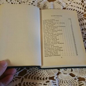 May include: An open book with a white cover and black text. The book's contents page lists topics such as "A Definition of Style", "The Value of Words", "Economy of Attention", and "Good Taste in Summary".