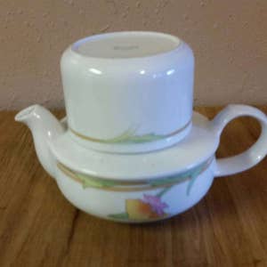 May include: White porcelain teapot with a floral design and a removable infuser. The teapot has a lid and a handle.