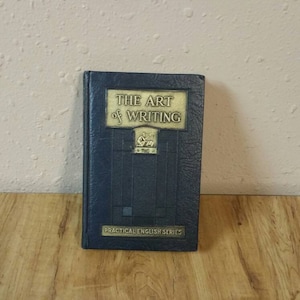 Può includere: Un libro rilegato in blu con il titolo "The Art of Writing" in lettere dorate. Il libro fa parte della "Practical English Series".