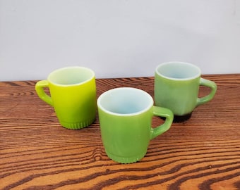 Set med 3 kaffe-/serveringsmuggar i glas, avokadogrönt, Anchor Hocking Fire King, mjölk, med grön och svart bas