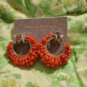May include: A pair of orange beaded hoop earrings with gold accents. The earrings are on a grey card with the text "Madewell" printed on it.