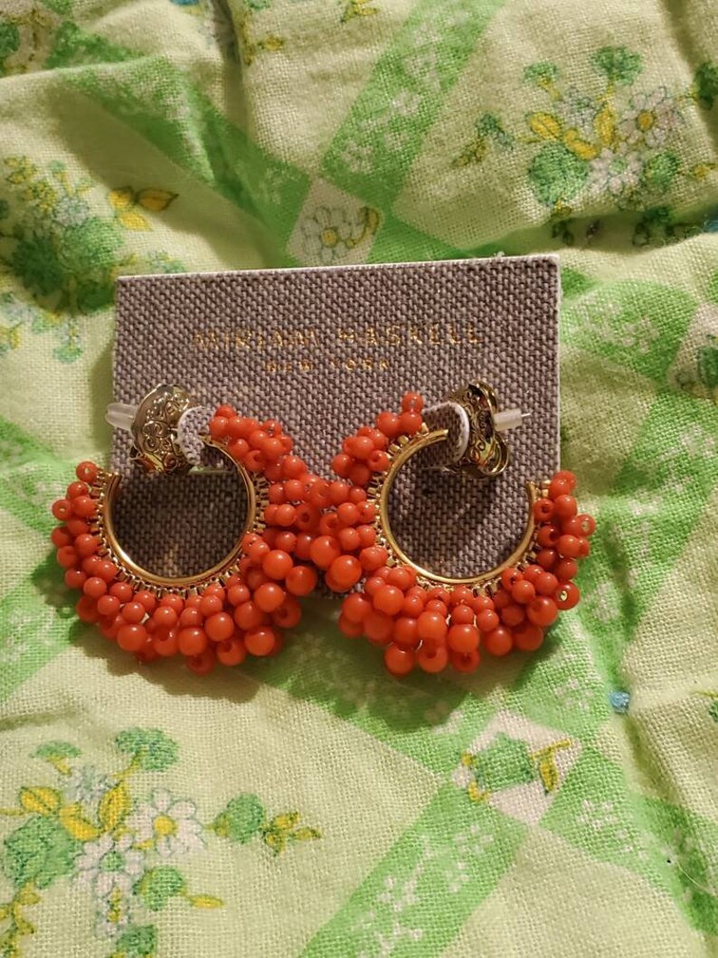 May include: A pair of orange beaded hoop earrings with gold accents. The earrings are on a grey card with the text "Madewell" printed on it.