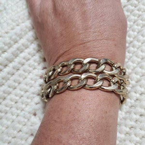 May include: A gold chain bracelet with two rows of thick, linked chains.